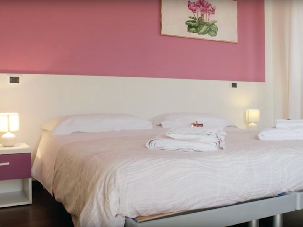Camera Ciclamino, letto matrimoniale e parete magenta