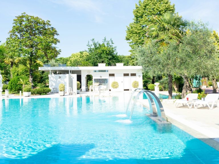 Piscina termale all'aperto di un hotel a Montegrotto Terme, con getti d'acqua e alberi intorno